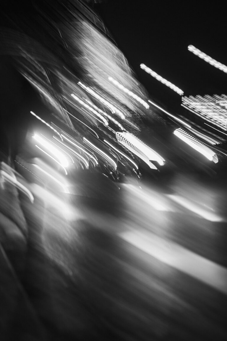 Abstrakte Schwarz-Weiß-Langzeitaufnahme mit verwischten Lichtstreifen vor dunklem Hintergrund.