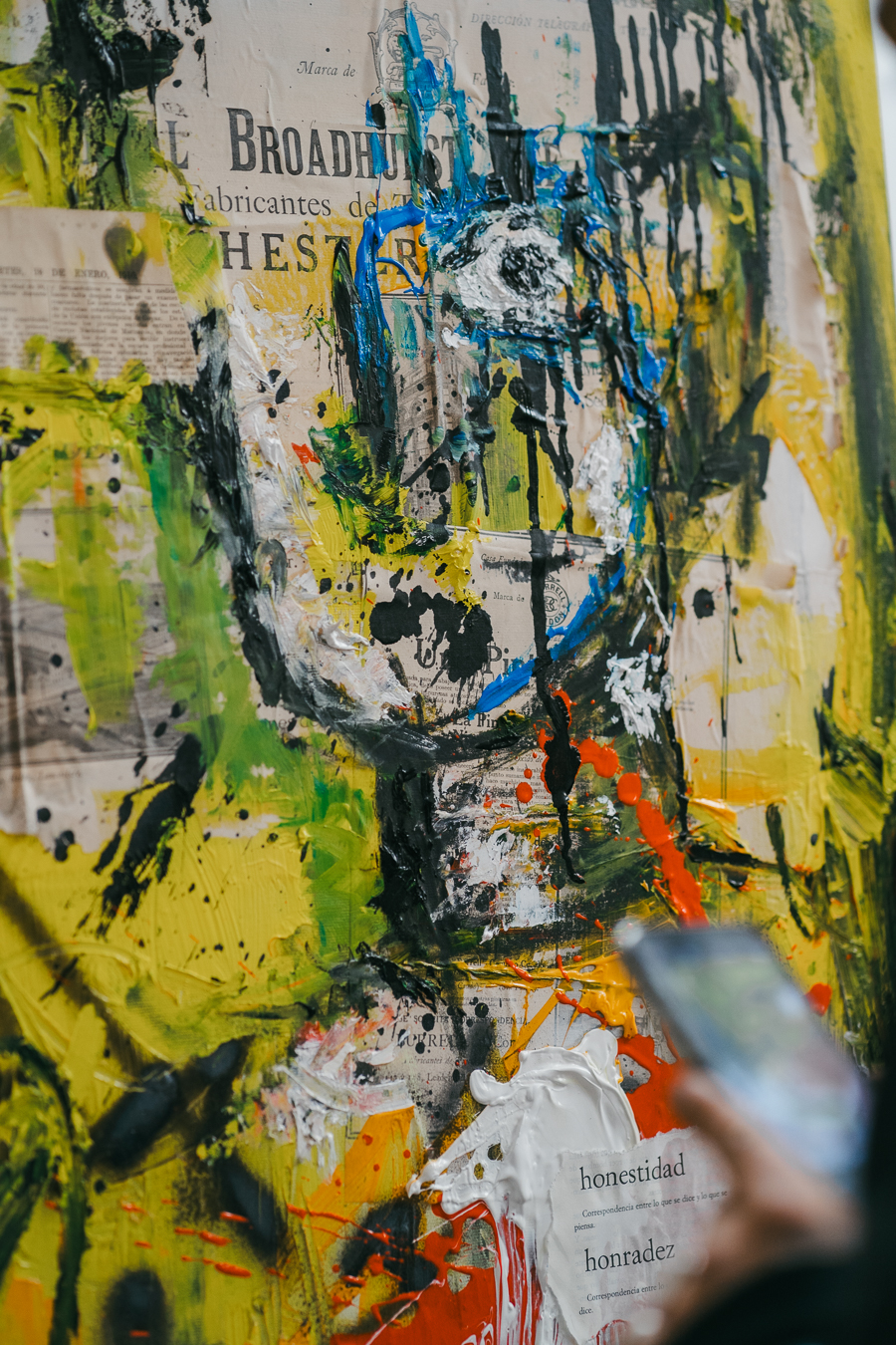 Mixed-media artwork featuring collage elements, newspaper text including 'BROADHURST', and thick applications of yellow, black, blue, and white paint.