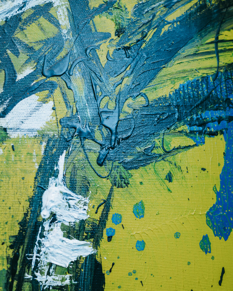 Close-up of an abstract painting featuring thick textured strokes of blue and white paint on a yellow and green canvas.