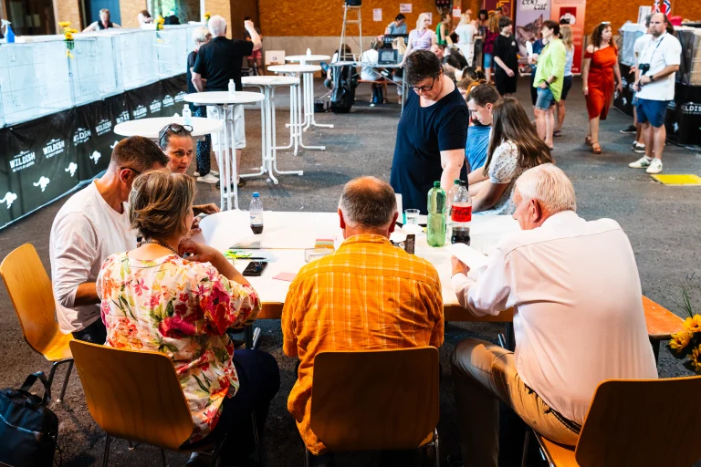 People gathered around tables indoors at a cat show.