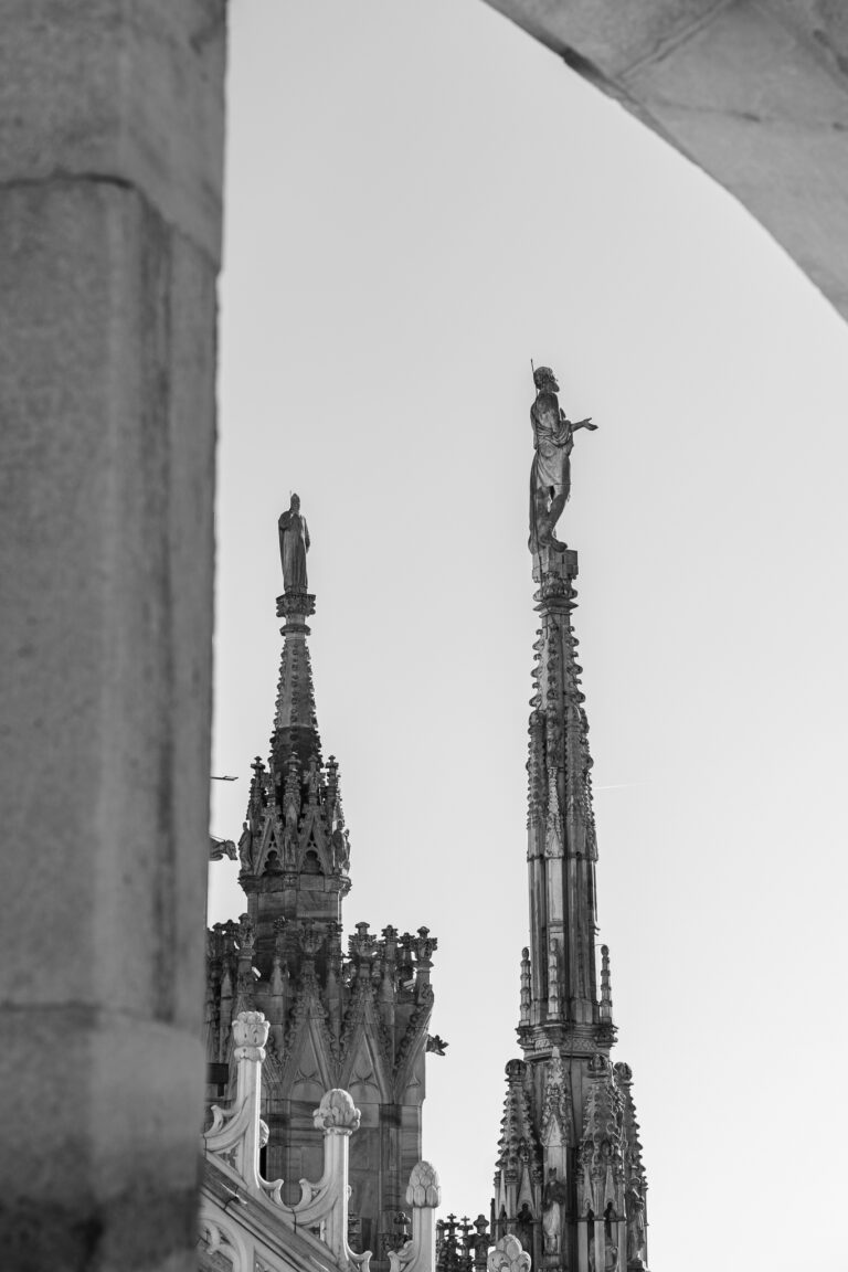 Eine Schwarz-Weiß-Ansicht detailreicher gotischer Fialen und Statuen des Mailänder Doms, eingerahmt von Architekturelementen.