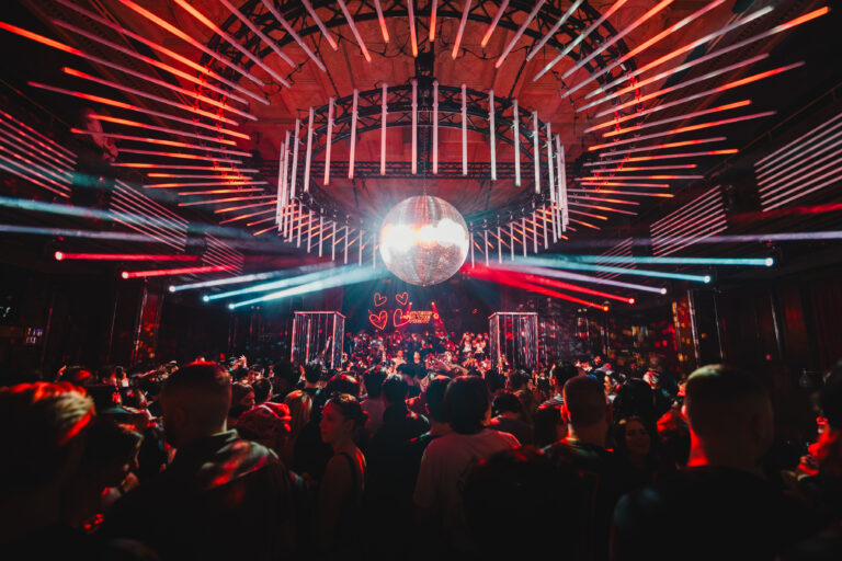 A crowded dance floor beneath a large disco ball and circular glowing light installations at Kaufleuten 2025.