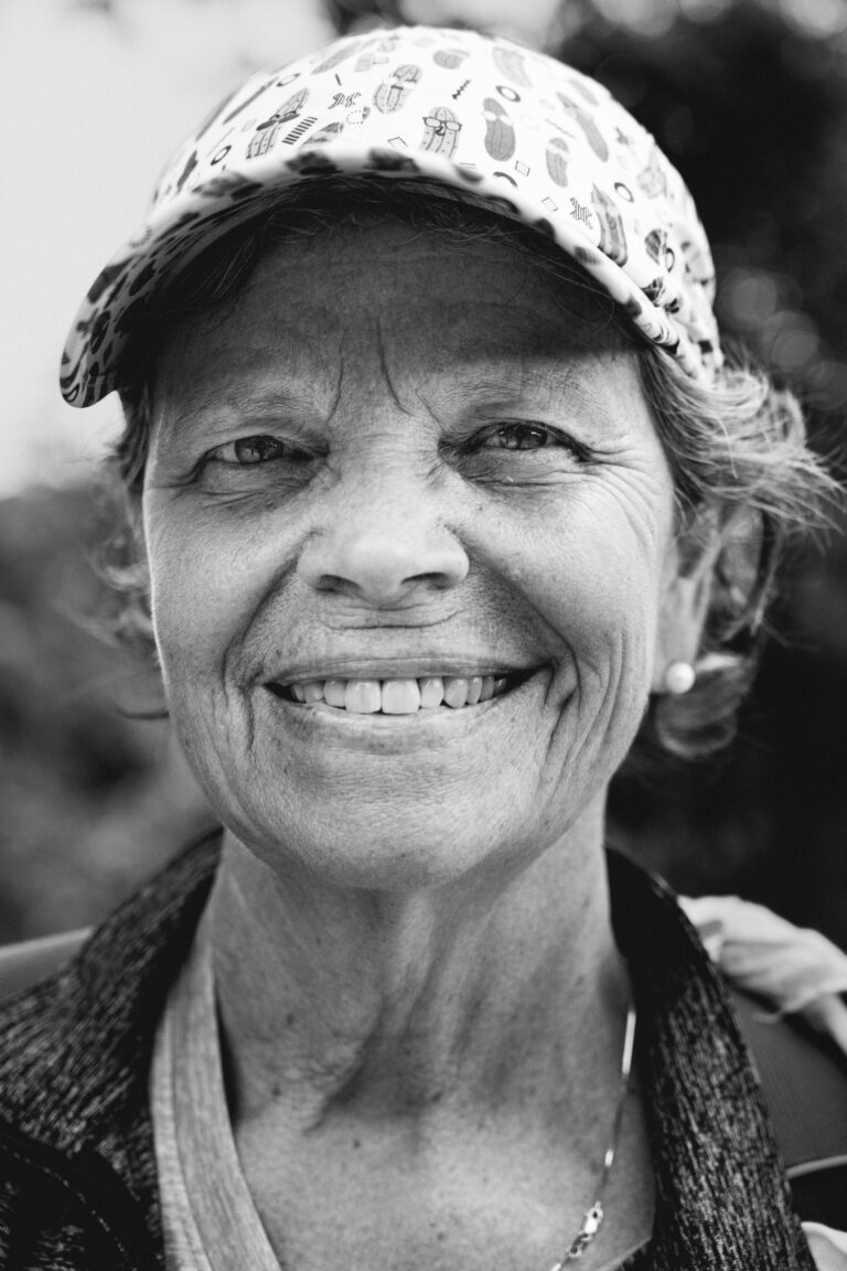 Close-up monochrome portrait of a smiling woman wearing a patterned cap.