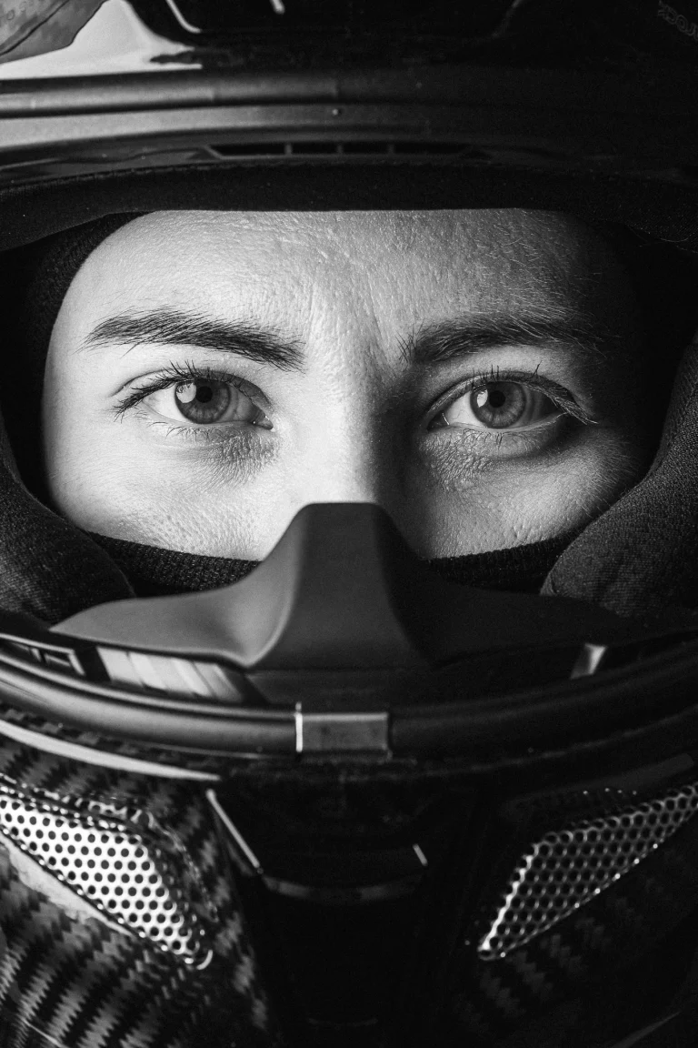 Close-up black and white portrait of a woman wearing a helmet.