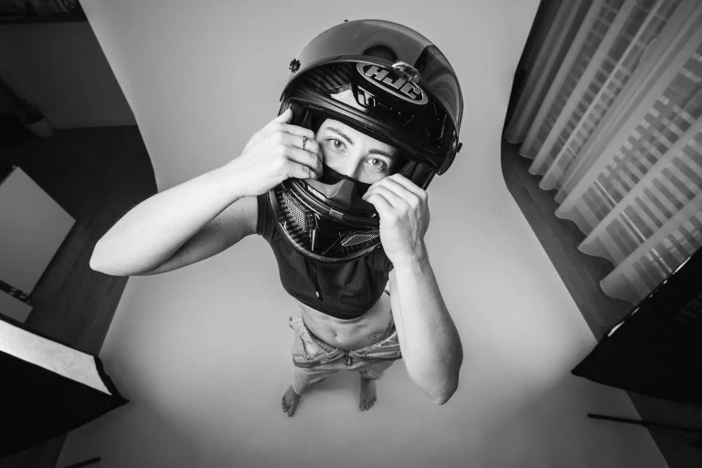 High-angle black and white portrait of a woman wearing a motorcycle helmet.