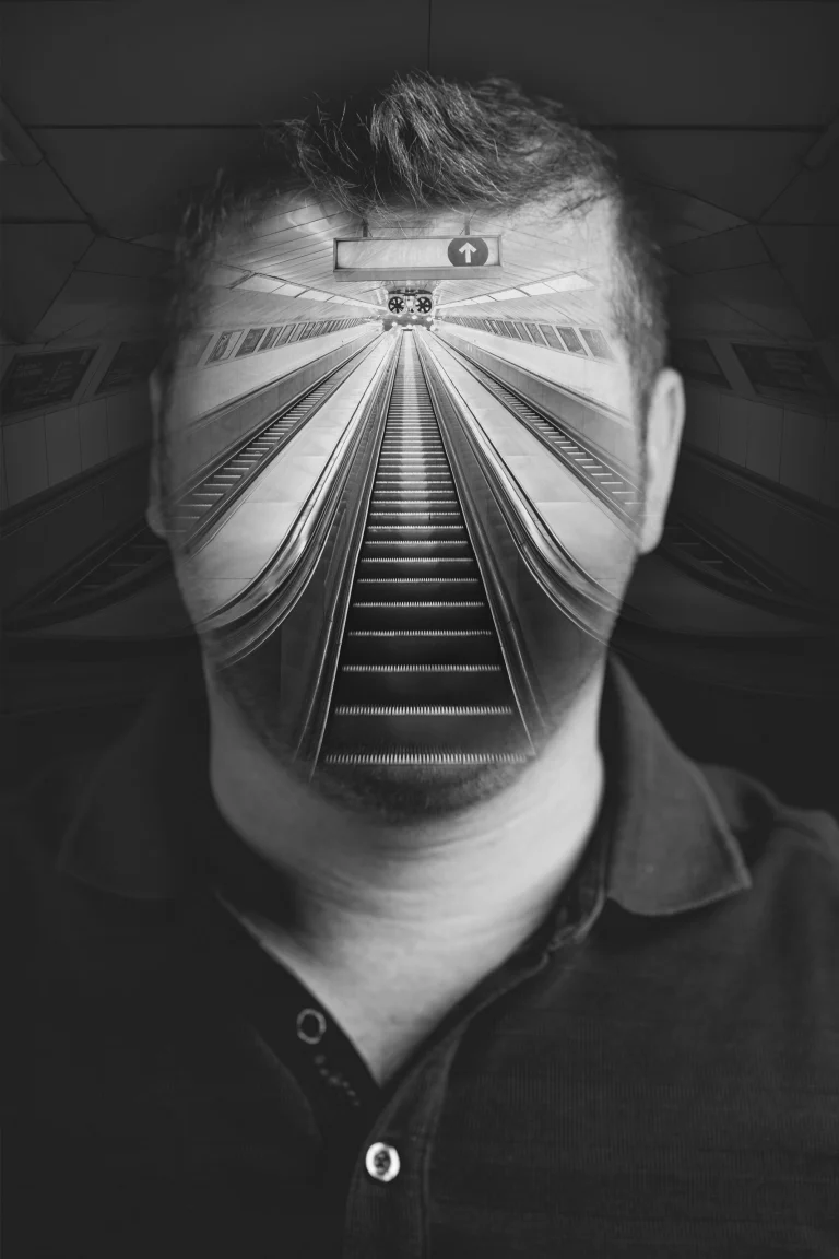 Monochrome photomontage showing a man's face merged with a symmetrical view of a subway station escalator.